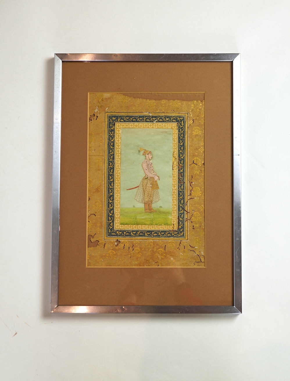 Mogul (Mughal) School , Profile Portrait of a Mogul dignitary, possibly Shah Jahan (1592-1666), full length, wearing court attire and a sword, standing in a landscape, watercolour miniature, 31cm x 20.5cm including borde